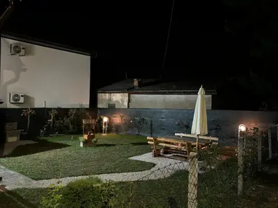 a backyard at night with a table and an umbrella at VillaH Weekend House in Visoko