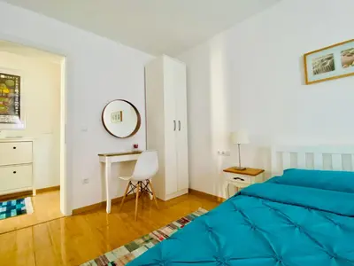 a bedroom with a blue bed and a desk at Moon Apartment Bihac in Bihać