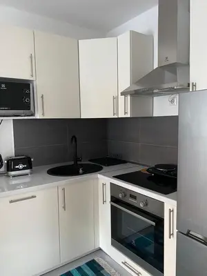 a kitchen with white cabinets and a sink and a stove at Moon Apartment Bihac in Bihać