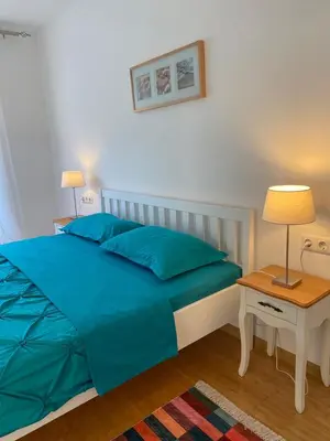 a bedroom with a bed with blue sheets and a table at Moon Apartment Bihac in Bihać