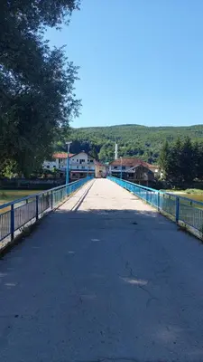 an empty road with a blue fence and a bridge at Apartman Mely in Kulen Vakuf
