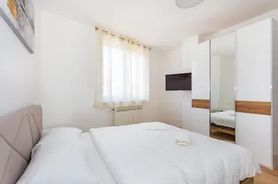 a white bedroom with two beds and a mirror at Apartman Krželj B2 in Livno