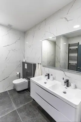 a bathroom with two sinks and a toilet and a mirror at Apartman Krželj B2 in Livno