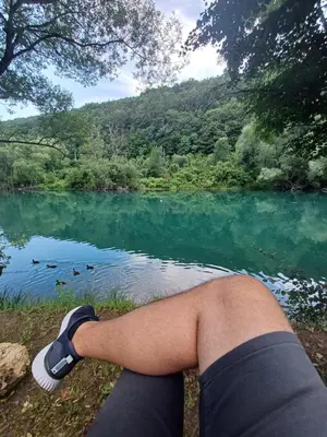 a persons leg sitting in front of a lake at AutoCamp Aqualand in Bihać