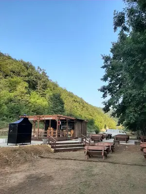 a wooden building with picnic tables in front of a hill at AutoCamp Aqualand in Bihać