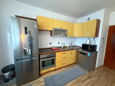 a kitchen with yellow cabinets and a stainless steel refrigerator at Luxury Apartment Tuzla in Tuzla