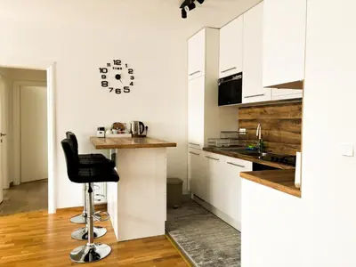 a kitchen with white cabinets and a bar with a black stool at Apartman Sučić in Livno