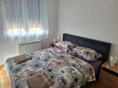 a bedroom with a bed with a floral comforter and pillows at Apartman Una banjaluka in Hiseti