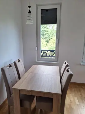 a dining room table with chairs and a window at Apartman Una banjaluka in Hiseti