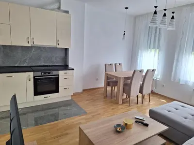 a kitchen and living room with a table and chairs at Apartman Una banjaluka in Hiseti