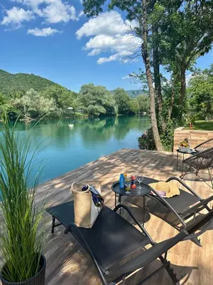 two chairs and a table on a deck next to a lake at Unavis Residence in Bihać