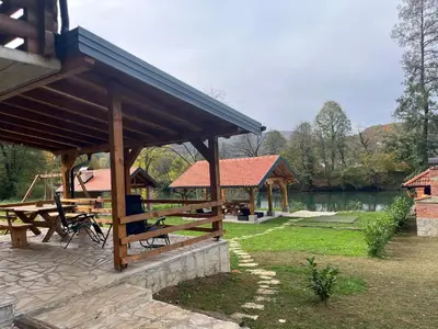 a wooden pavilion with a picnic table next to a lake at Vikendica Krupa na Vrbasu in Banja Luka