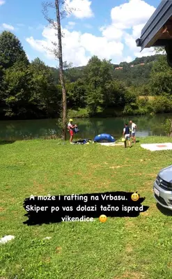 a group of people standing in the grass near a lake at Vikendica Krupa na Vrbasu in Banja Luka