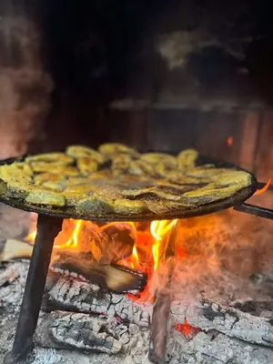 a pizza sitting on a table over a fire at A&S vikendica Vlašić in Šišava
