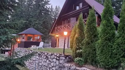 a house with a stone wall and a bench in front of it at A&S vikendica Vlašić in Šišava