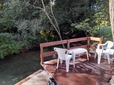 three white chairs and a table on a wooden deck at Pure Nature in Bihać