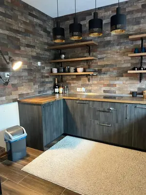 a kitchen with wooden cabinets and a brick wall at Una in Bihać