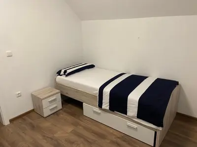 a small bedroom with a bed and a wooden floor at Una in Bihać