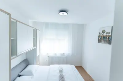 a white bedroom with a bed and a window at Apartman Krželj B4 in Livno