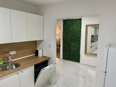 a kitchen with white cabinets and a green wall at ANET Apartman Visoko in Visoko
