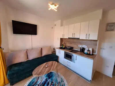 a small living room with a couch and a kitchen at Apartmani Sarah 3 Tuzla in Tuzla