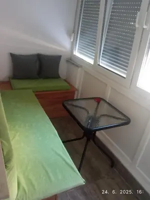 a room with a bed and a table and two windows at Apartman Dijana in Livno