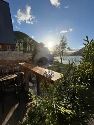 a wooden table with a fireplace next to a body of water at Vikendica - Rajski Poluotok in Jajce