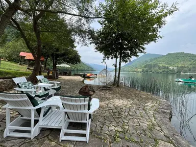 a group of white chairs sitting next to a lake at Vikendica - Rajski Poluotok in Jajce