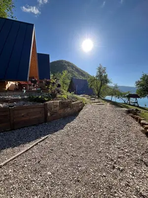 a gravel road leading to a building with the sun in the sky at Vikendica - Rajski Poluotok in Jajce