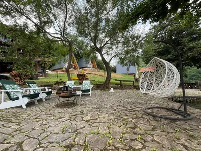 a group of chairs sitting on a patio under a tree at Vikendica - Rajski Poluotok in Jajce