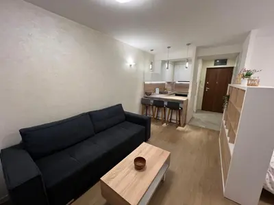 a living room with a black couch and a table at Apartman Sara in Zenica