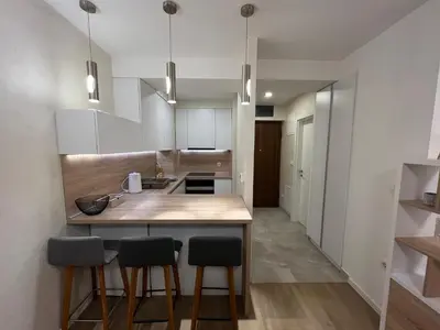a kitchen with white cabinets and a wooden island with bar stools at Apartman Sara in Zenica