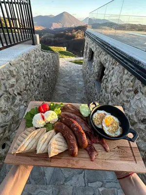 a tray of breakfast food with sausage and eggs on a table at Zemunice Knezevic in Banja Luka