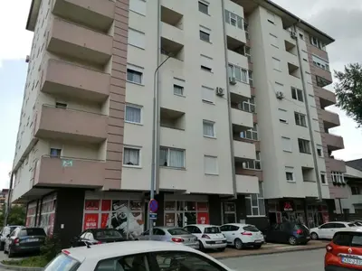 a large apartment building with cars parked in front of it at Apartman Jana in Doboj