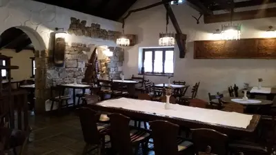 a restaurant with tables and chairs and a stone wall at Farm Stay Čardaklije in Kulen Vakuf