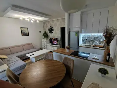 a living room with a table and a kitchen at APARTMAN KRPELJ Banja Luka in Budžak
