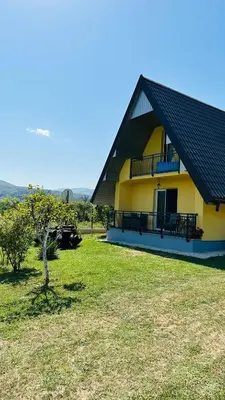 a yellow house with a black roof and a yard at B&B Hills Bihać in Bihać