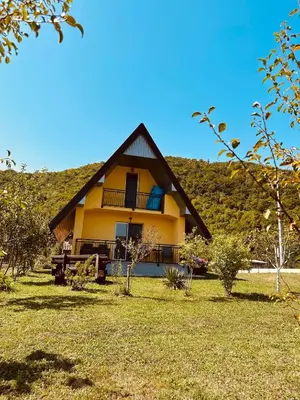 a large yellow house with a hill in the background at B&B Hills Bihać in Bihać