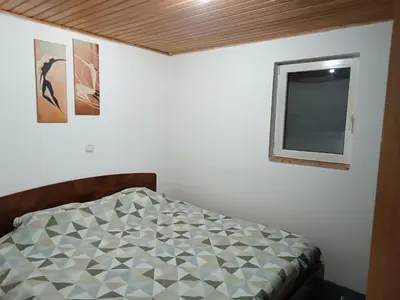 a bed in a room with a mirror and a window at Mountain Apartment Vlašić Babanovac in Vlasic