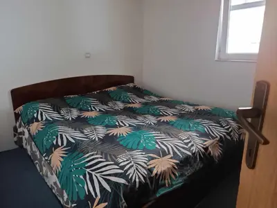 a bed in a room with a bedspread with palm leaves at Mountain Apartment Vlašić Babanovac in Vlasic