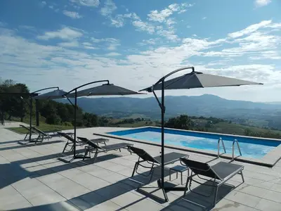a pool with chairs and umbrellas on a patio at Villa Vista in Banja Luka