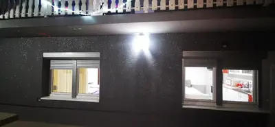 two windows on the side of a building with a light at Apartman Delic in Lukavac