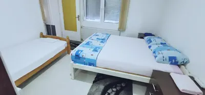 a bedroom with two beds and a window at Apartman Delic in Lukavac