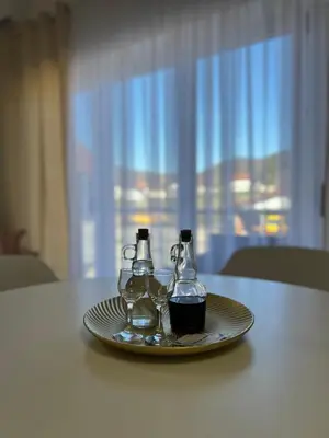 two glass bottles on a plate on a table at Apartment Magnolia in Banja Luka