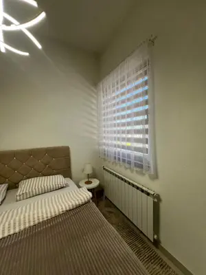 a bedroom with a bed and a window with a radiator at Apartment Magnolia in Banja Luka
