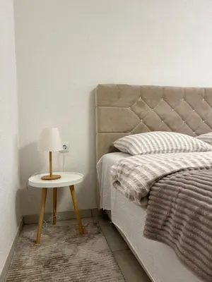 a bed with a night stand next to a bed with a lamp at Apartment Magnolia in Banja Luka