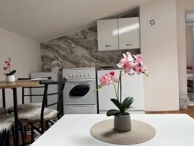 a kitchen with a table with a vase with pink flowers at Apartment Star in Jajce