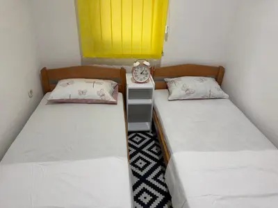 two beds in a room with a clock on a night stand at Apartment Star in Jajce