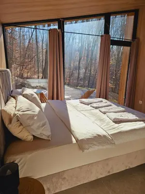 a bed in a bedroom with a large window at Apartman Košuta in Laktaši