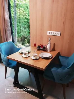 a wooden table with two chairs and a glass of wine at Apartman Košuta in Laktaši